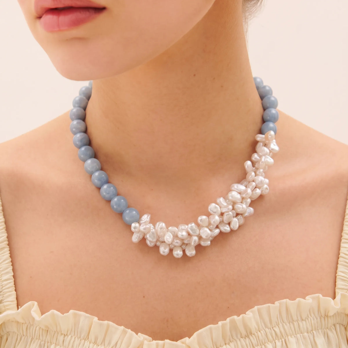 Woman wearing an angelite and petal-shaped baroque pearl layered necklace