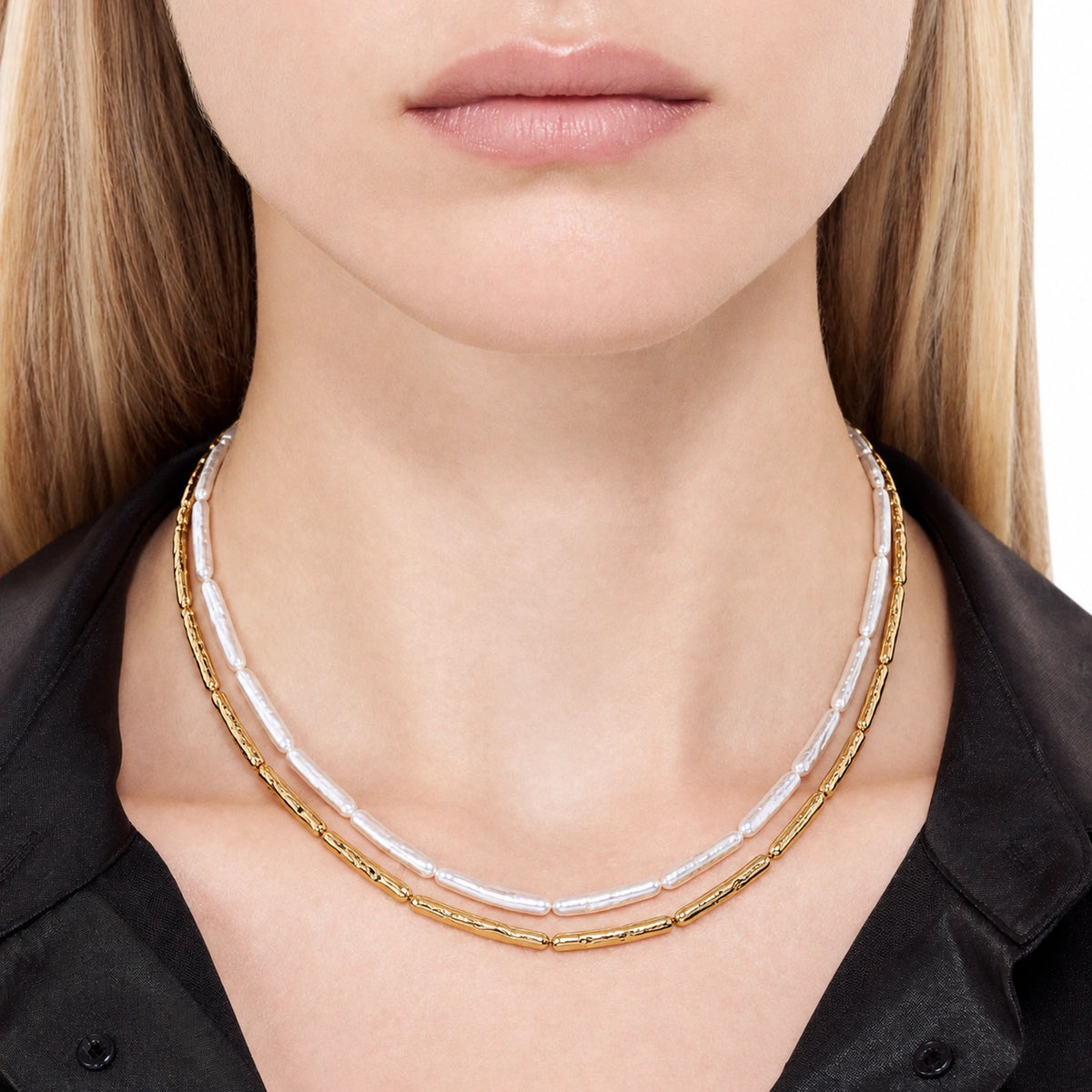 Woman wearing a double-layer necklace with white baroque pearls and hammered gold tube chain