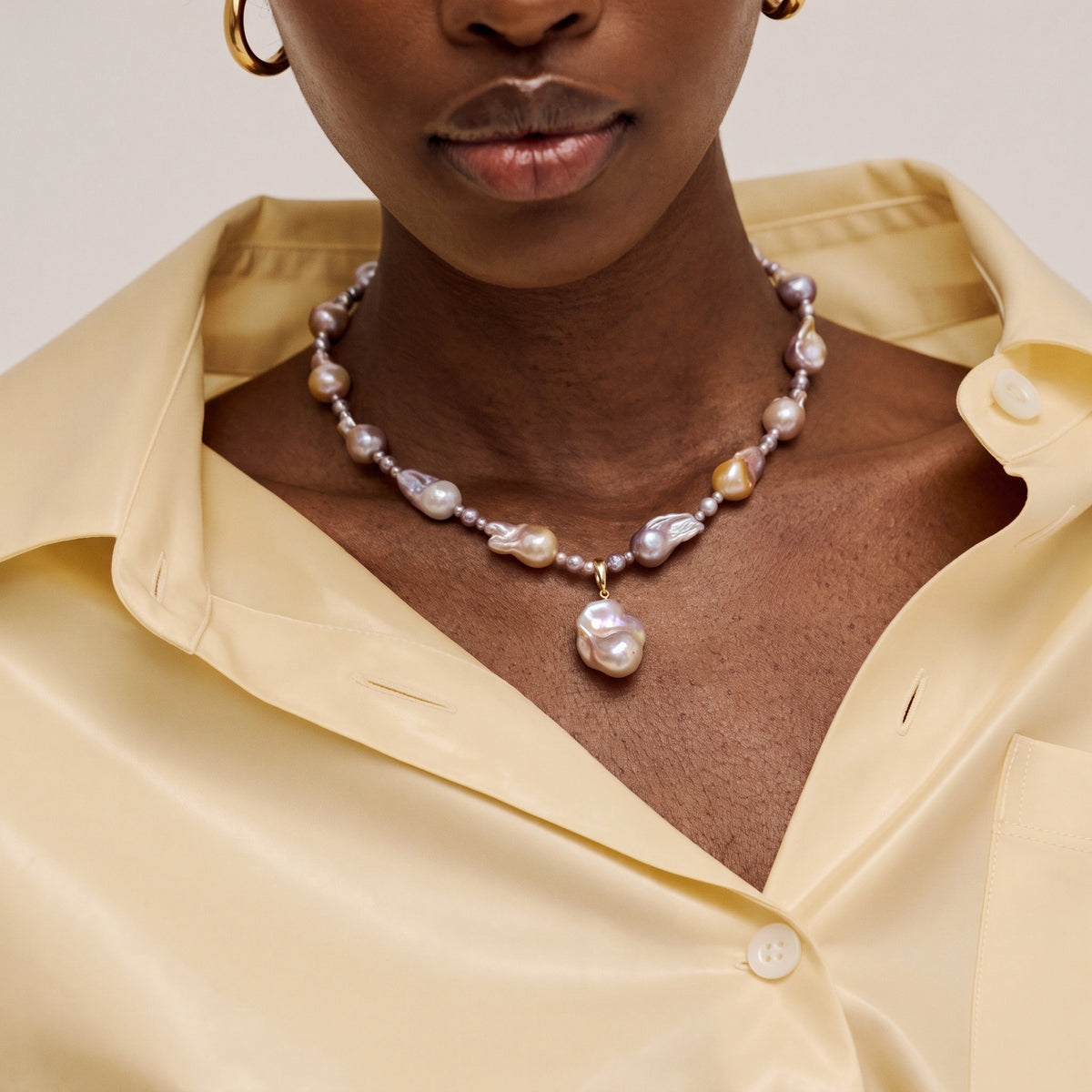 Woman wearing a multicolor baroque pearl necklace with a single pearl drop pendant