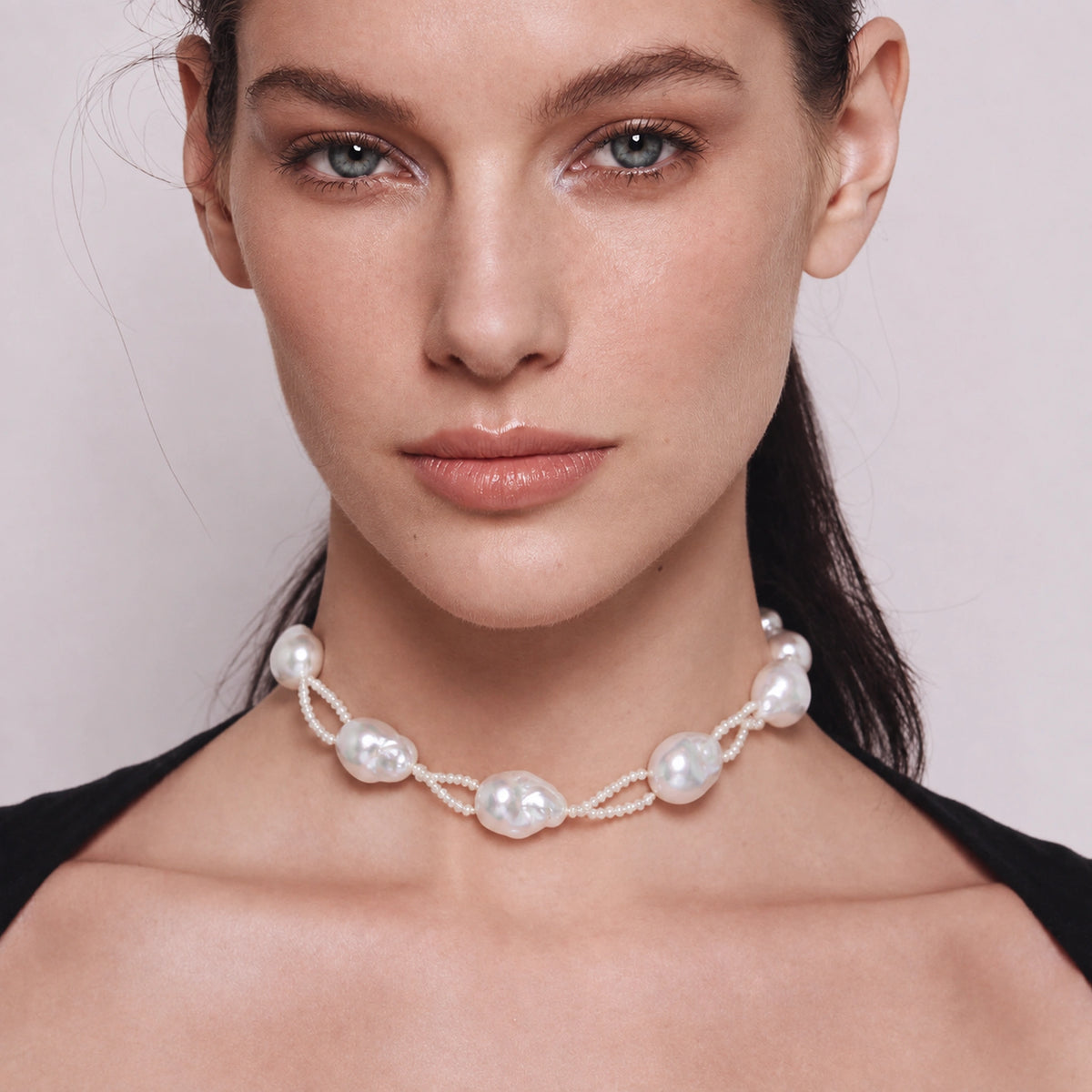 Close-up of a woman wearing a baroque pearl necklace, front neck view