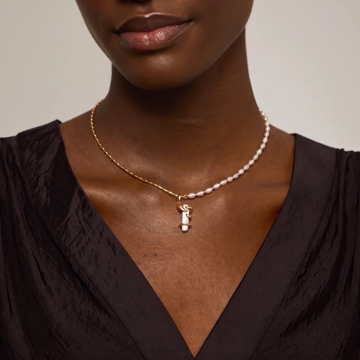 Woman wearing a drift pearl necklace with a twisted metal and pearl pendant, close-up