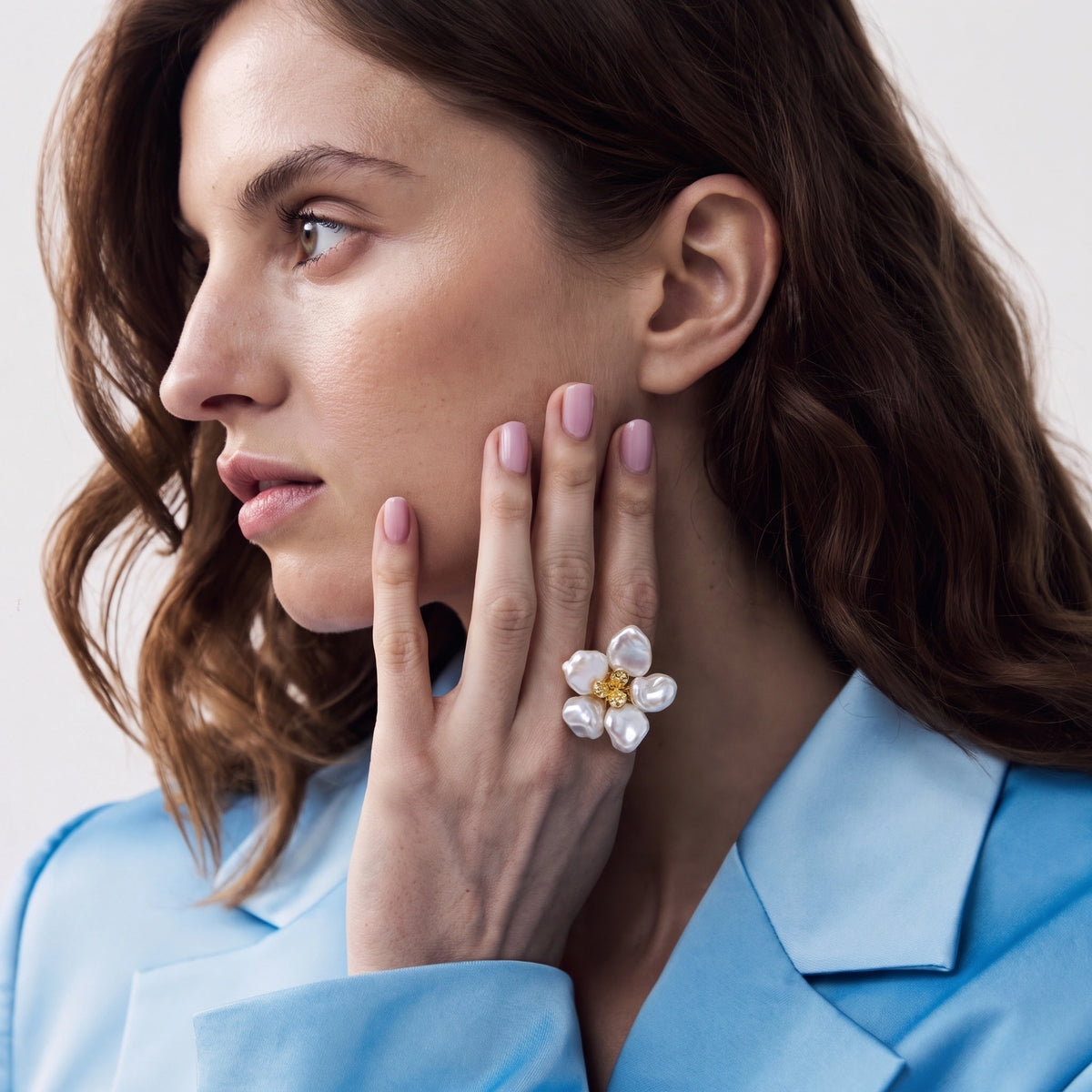 Side profile of a woman wearing a flower-shaped keshi pearl ring near her cheek