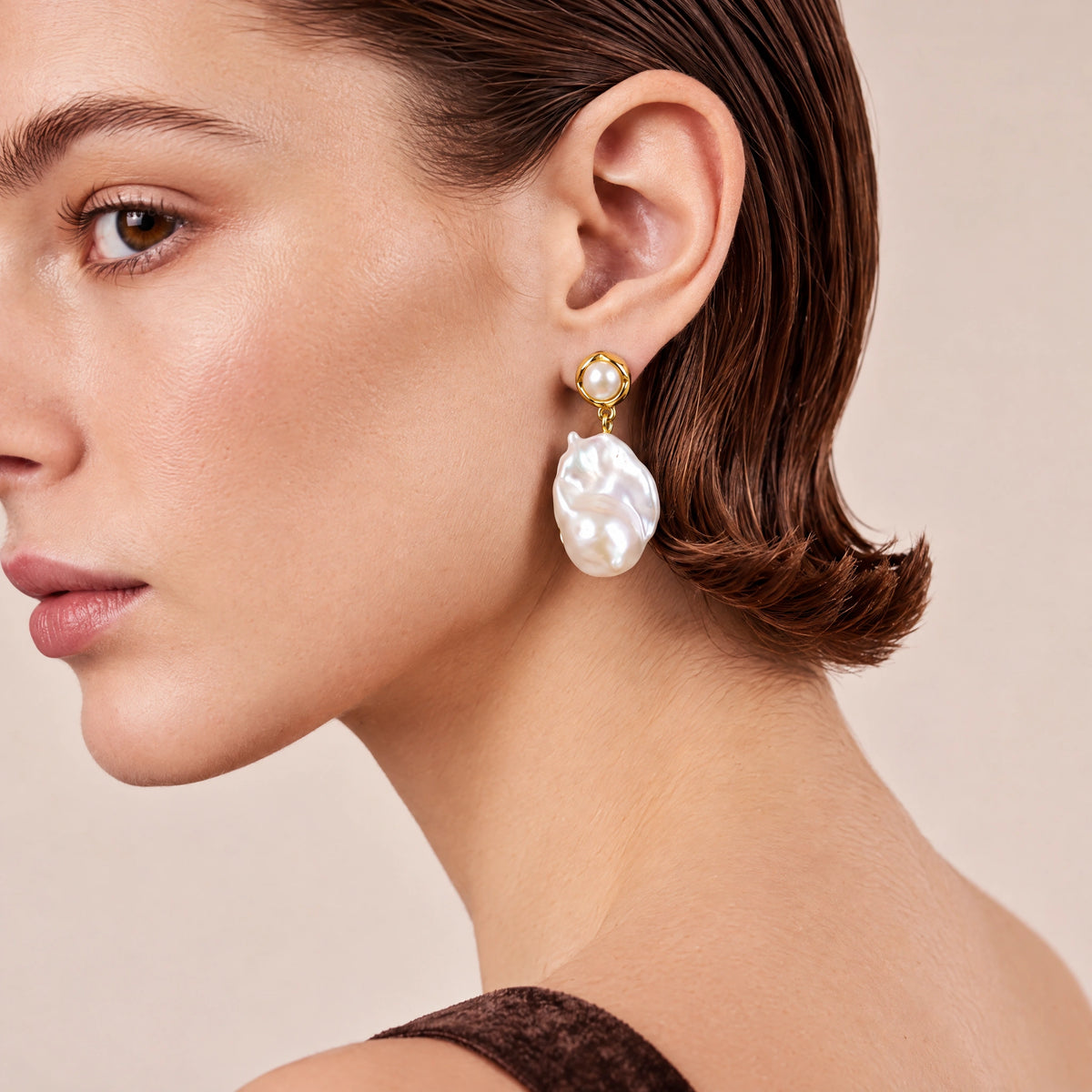 Close-up side profile of a gold ring stud earring with a baroque pearl drop
