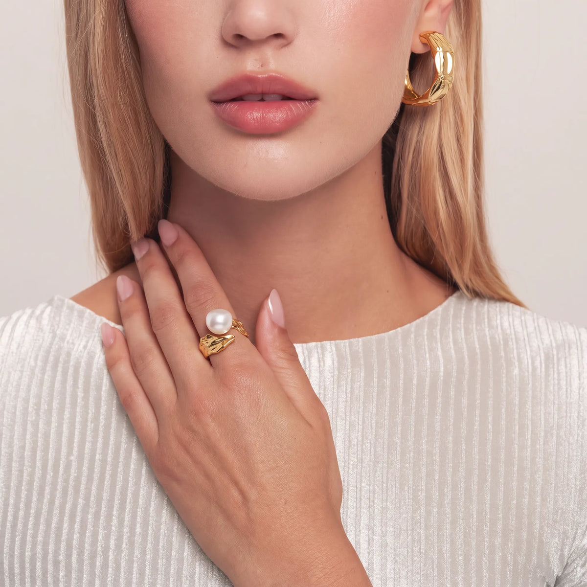 Woman wearing a gold organic branch open ring with a white round pearl, paired with matching hammered gold earrings