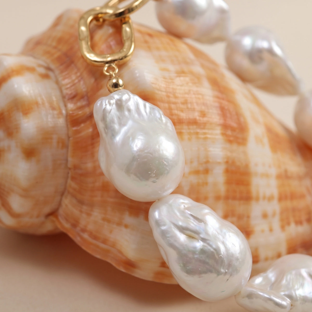 Close-up of the gold clasp and teardrop pearl charms on a baroque pearl bracelet