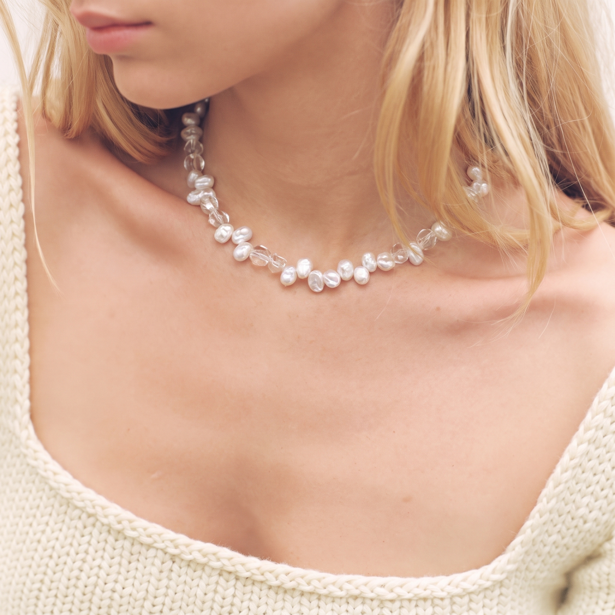 Woman wearing an irregular white pearl and clear bead necklace, close-up