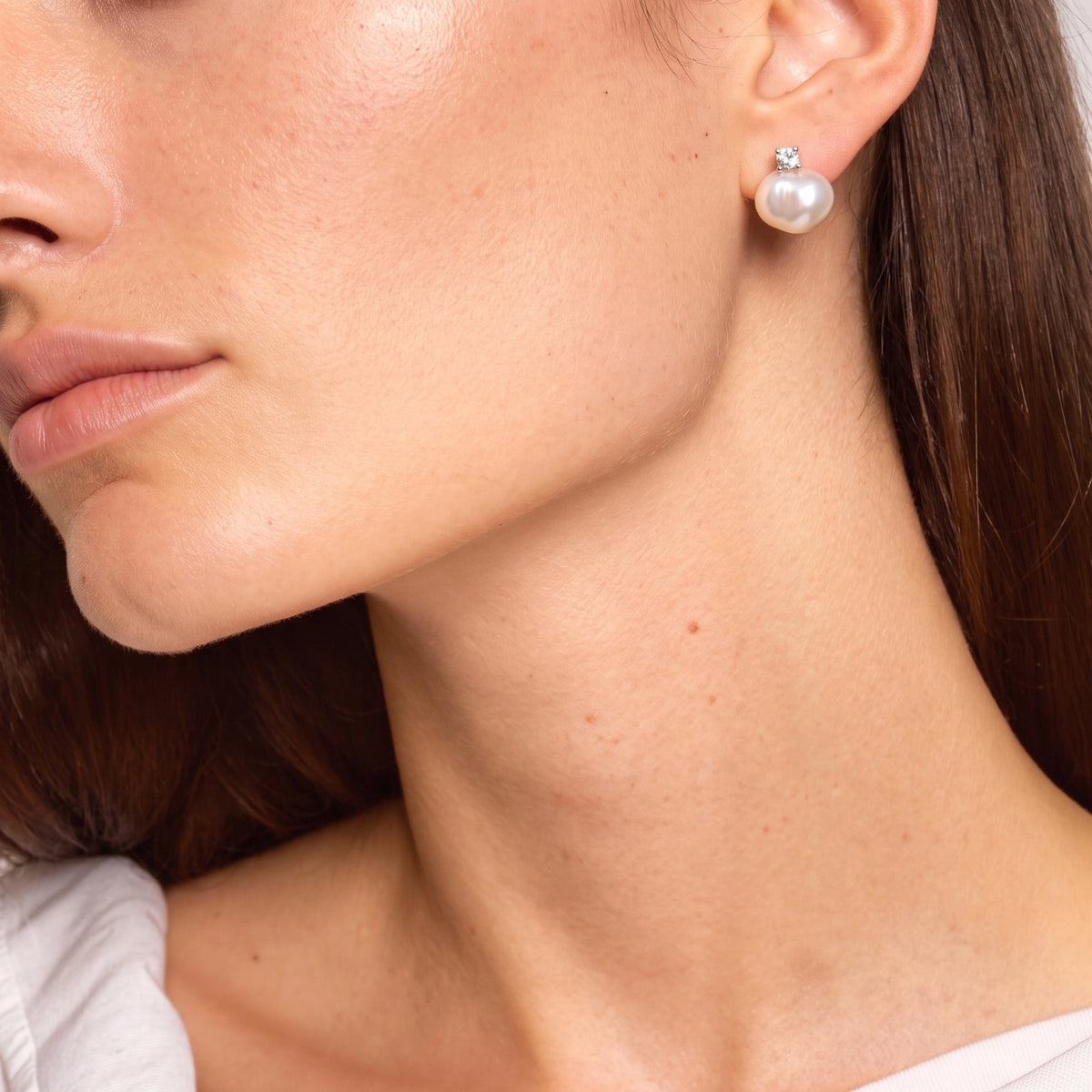 Close-up of a round baroque pearl stud earring with a small crystal accent