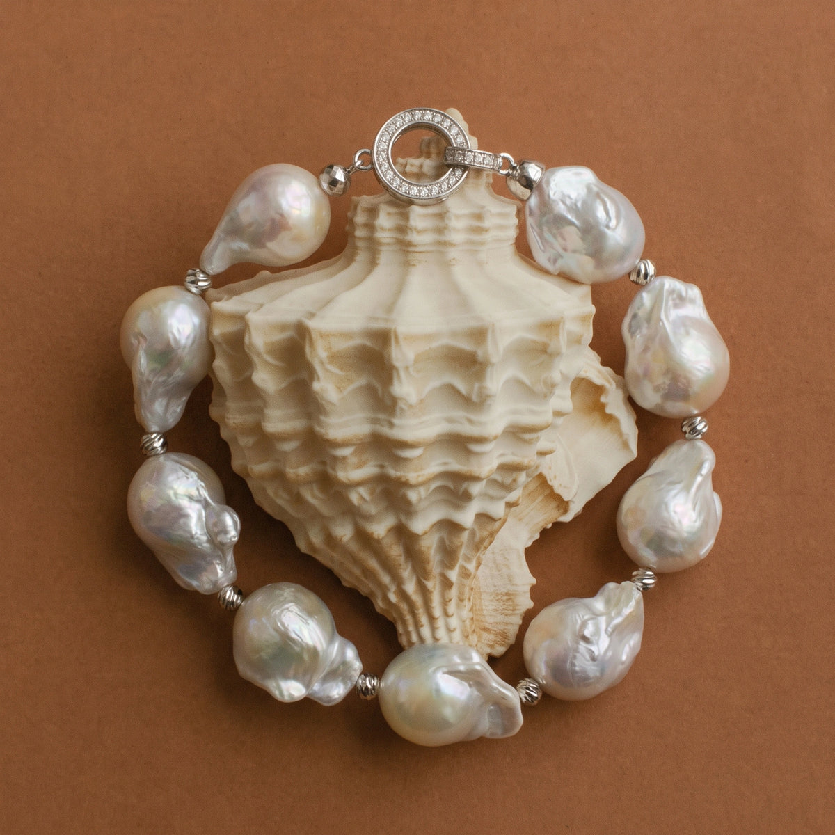 Lunar Form baroque pearl bracelet laid flat around a seashell, showing the full circle of pearls