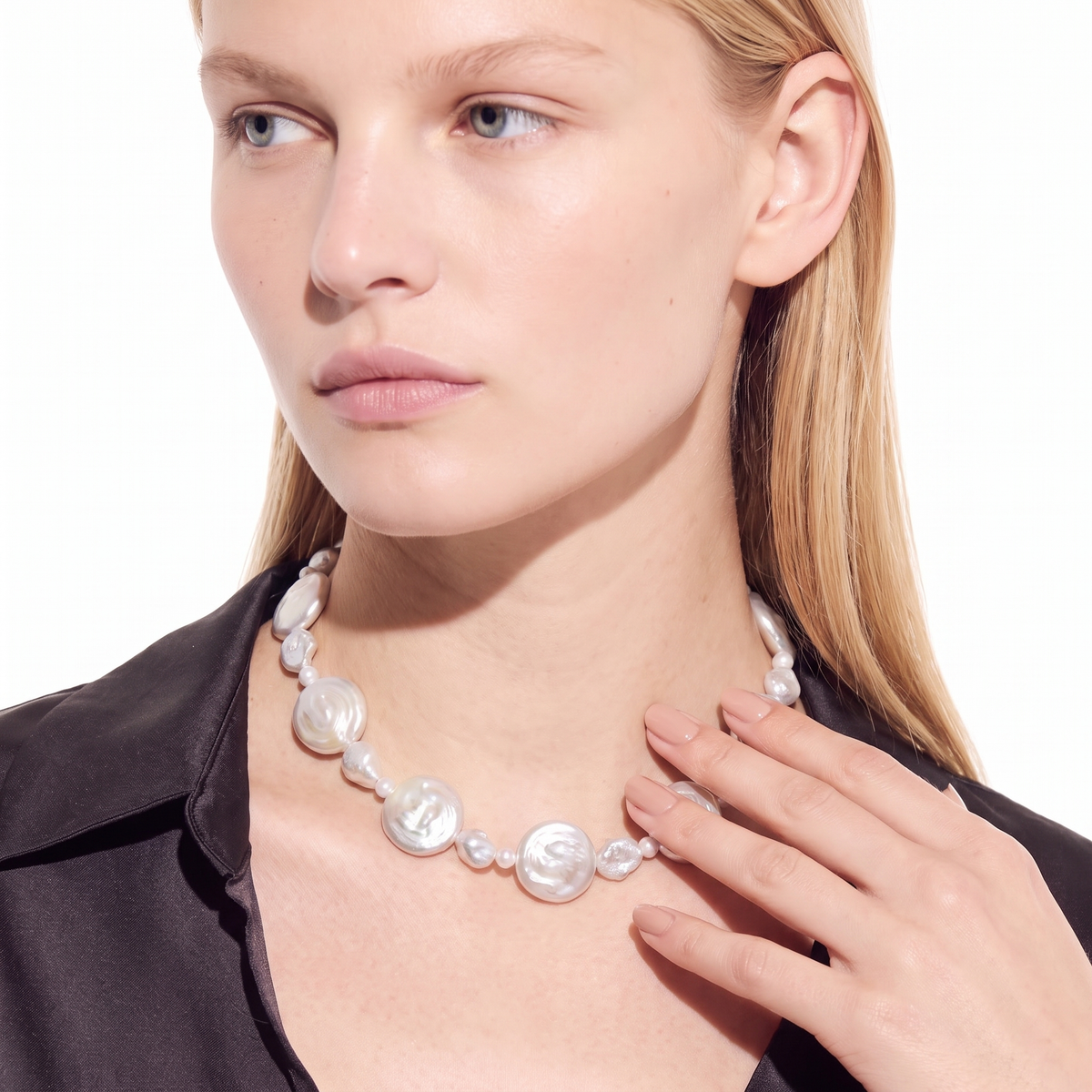 Close-up of a woman wearing a graduated white pearl necklace, three-quarter angle