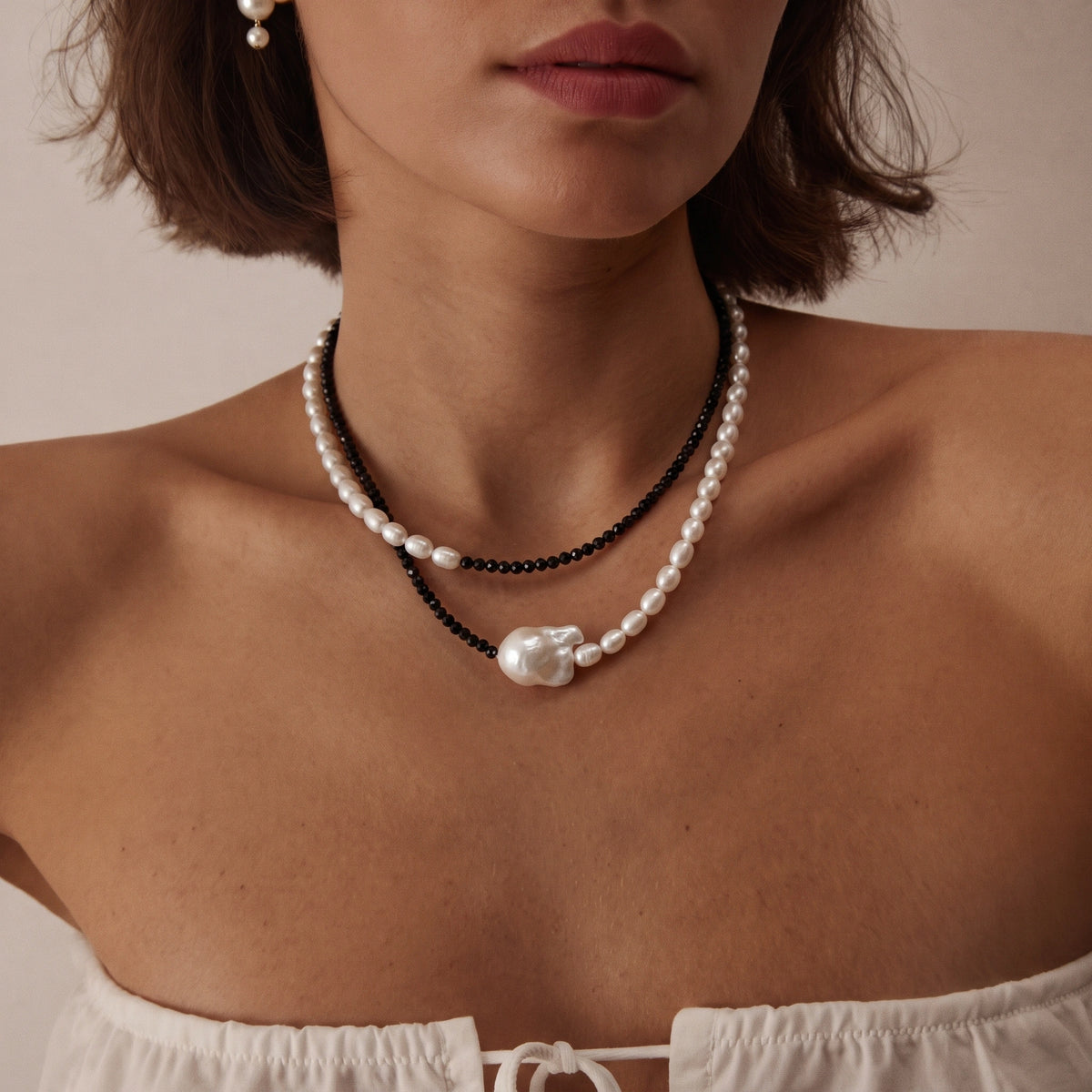 Close-up of a double-layer necklace with black beads and a large white baroque pearl