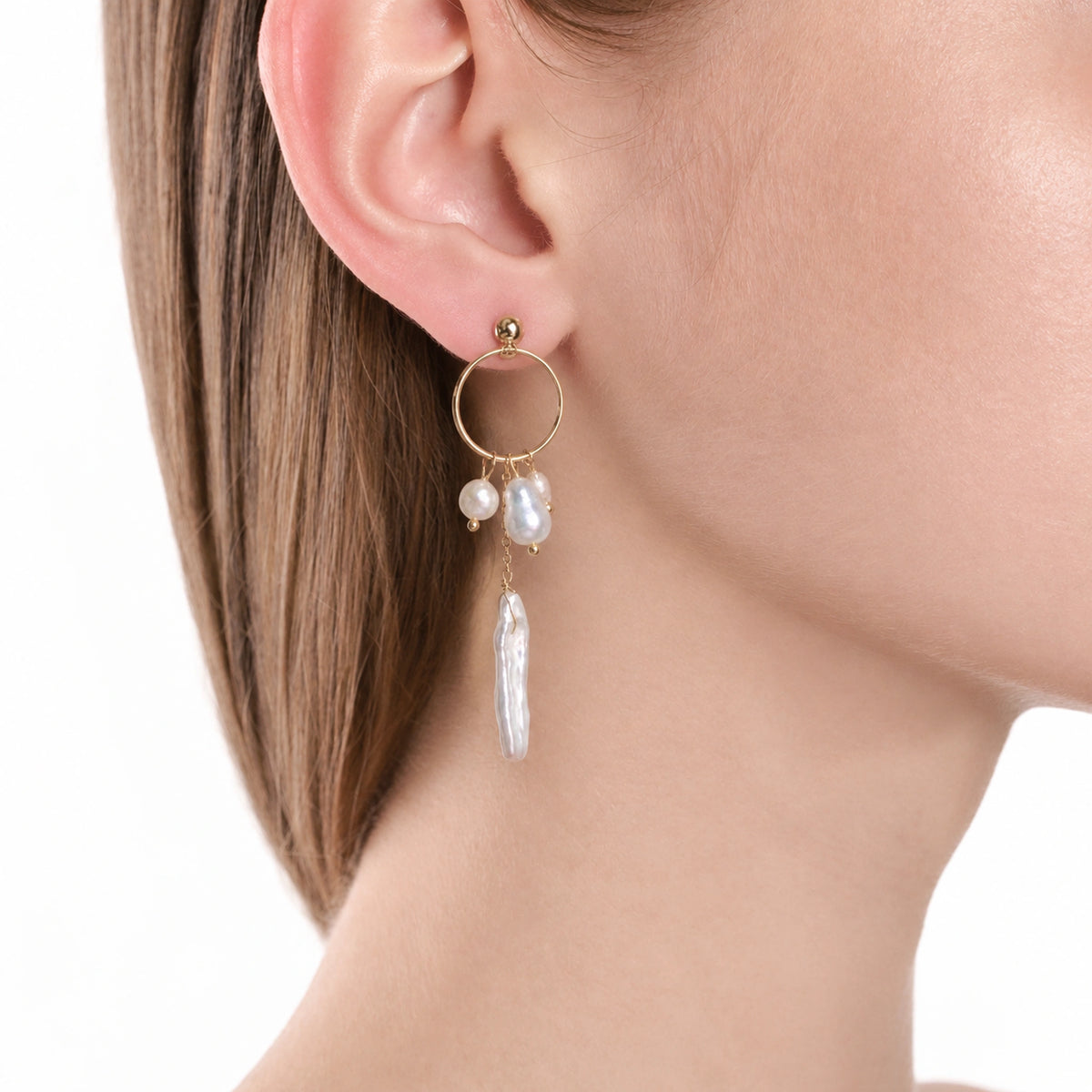 Close-up of a gold stud earring with a hanging ring and three keshi pearl drops