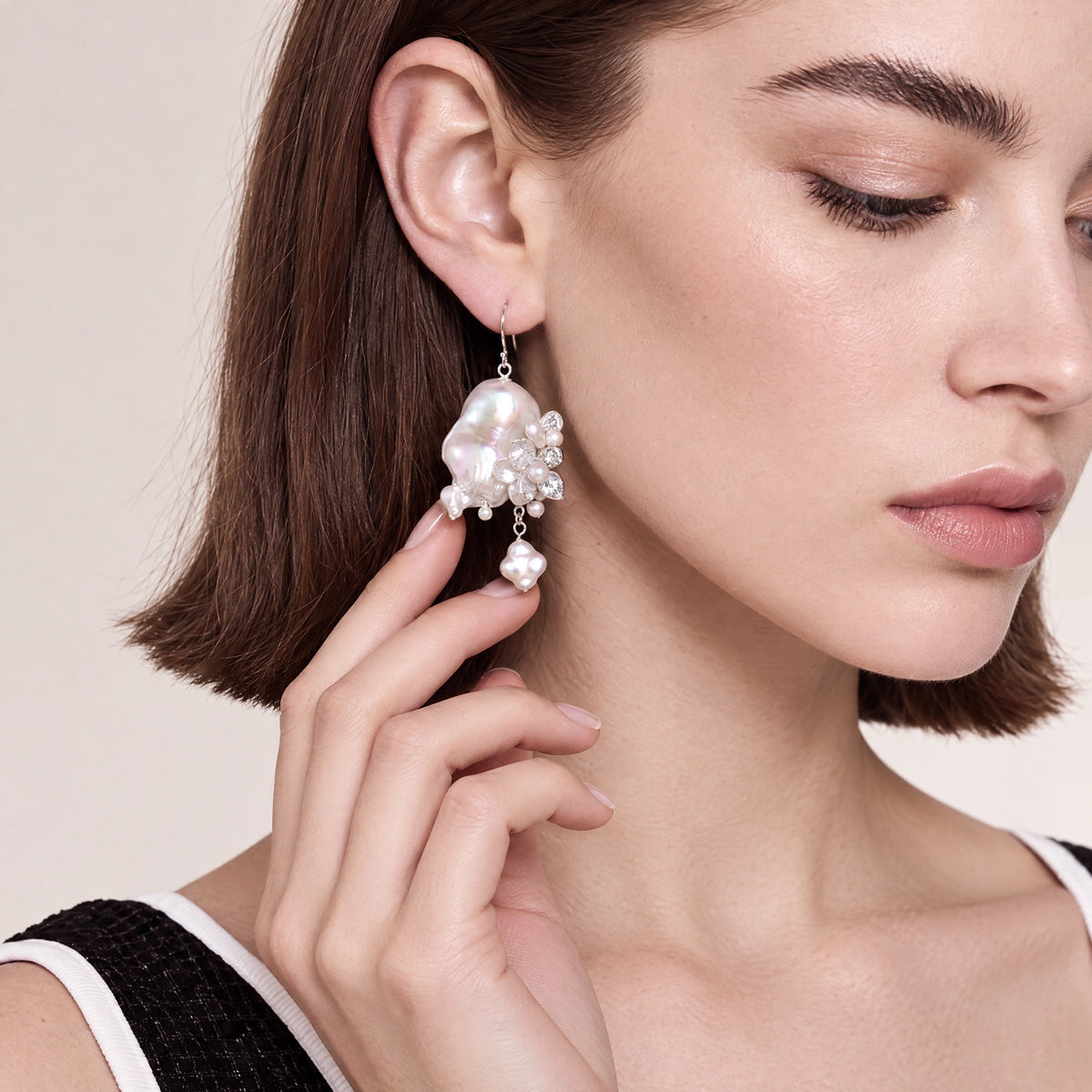 Close-up of a baroque pearl earring with a silver flower charm set with small crystals