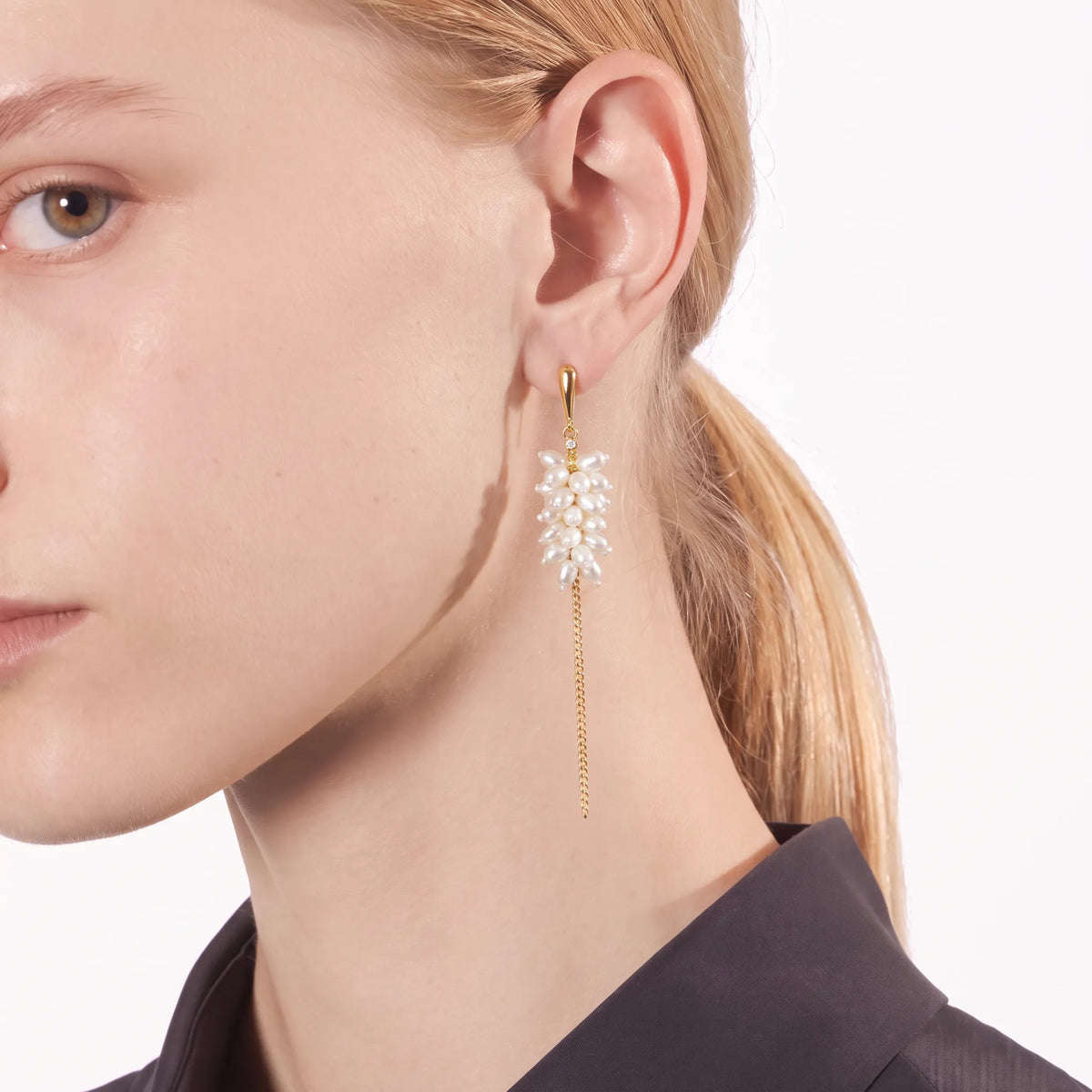 Close-up of a pearl blossom cluster earring with crystal accent and gold chain drop