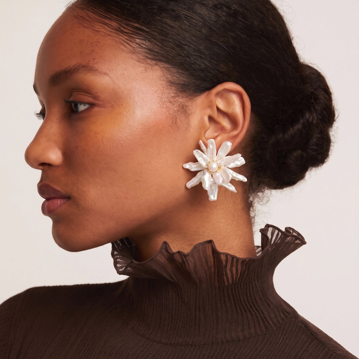 Close-up of a large flower-shaped earring with white keshi pearl petals and a round pearl center