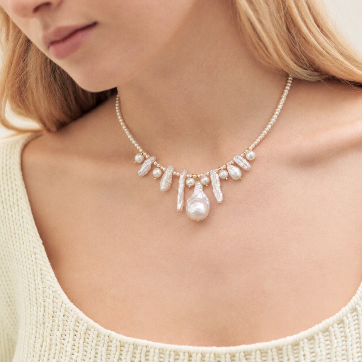 Woman wearing a seed pearl necklace with an asymmetric fringe of baroque pearl drops