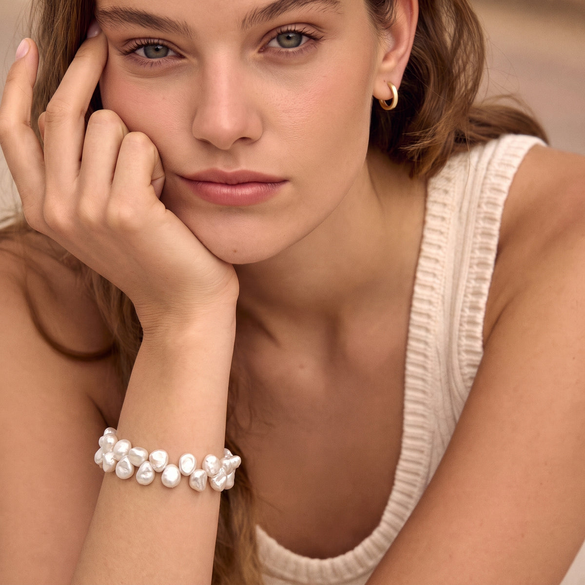 Woman resting her chin on her hand, wearing a white keshi pearl bracelet