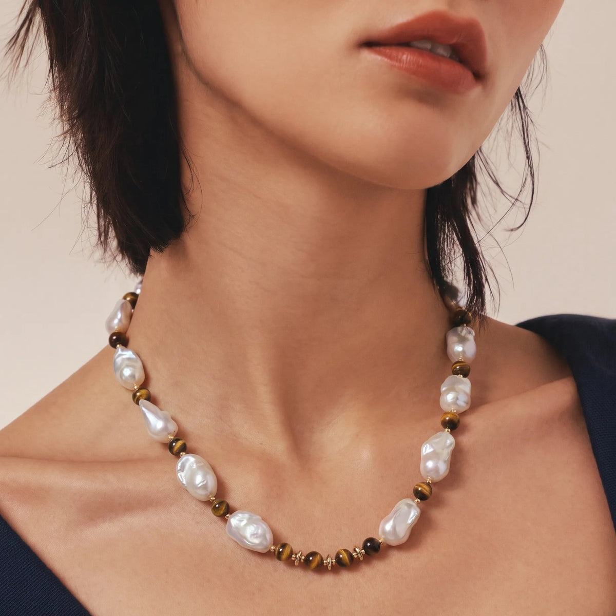 Woman wearing a tiger eye and baroque pearl beaded necklace, front neck view