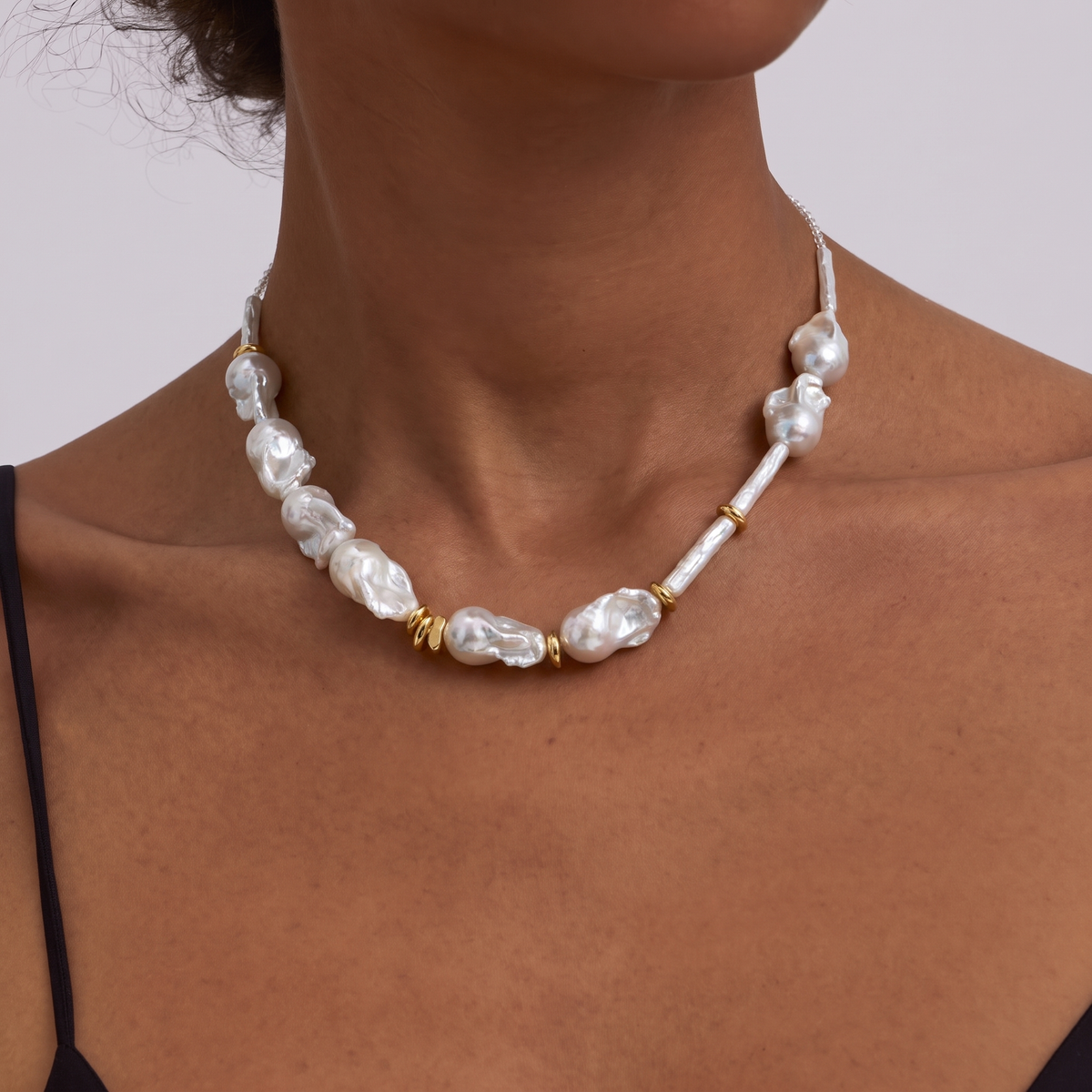 Woman wearing a baroque pearl necklace with gold ring spacers